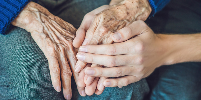 A young person's hands cradling an older person's hands